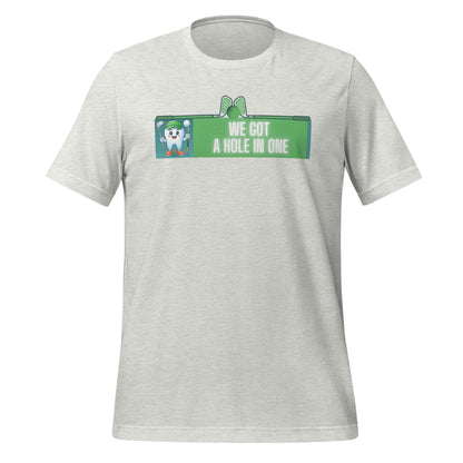 Cute dentist t-shirt showcasing an adorable tooth character in golf attire, joyfully celebrating a ‘hole in one’ achievement, perfect for dentist and dental professionals seeking unique and thematic dental apparel. Ash color, front view.