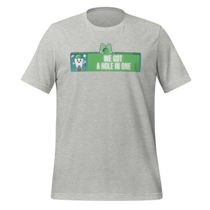 Cute dentist t-shirt showcasing an adorable tooth character in golf attire, joyfully celebrating a ‘hole in one’ achievement, perfect for dentist and dental professionals seeking unique and thematic dental apparel. Athletic heather color, front view.