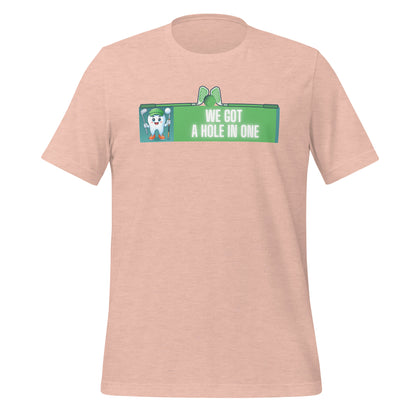 Cute dentist t-shirt showcasing an adorable tooth character in golf attire, joyfully celebrating a ‘hole in one’ achievement, perfect for dentist and dental professionals seeking unique and thematic dental apparel. Heather prism peach color, front view.
